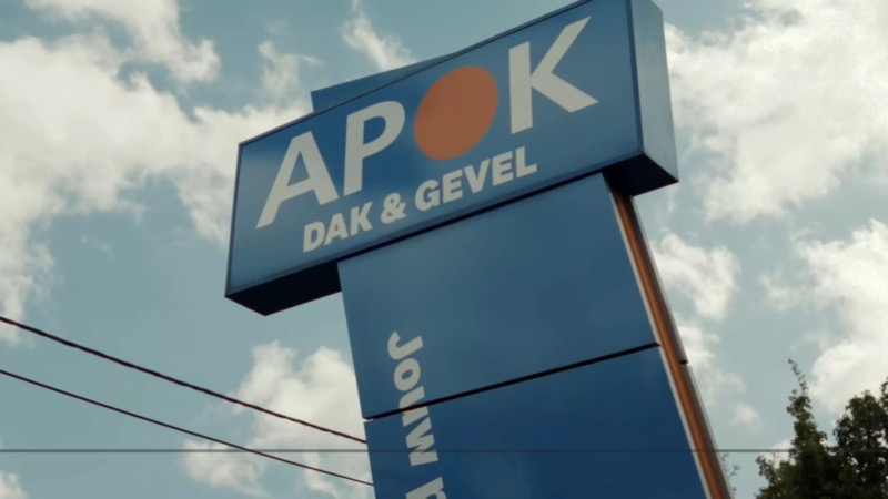 Het uithangbord van APOK Dak & Gevel tegen een blauwe lucht.